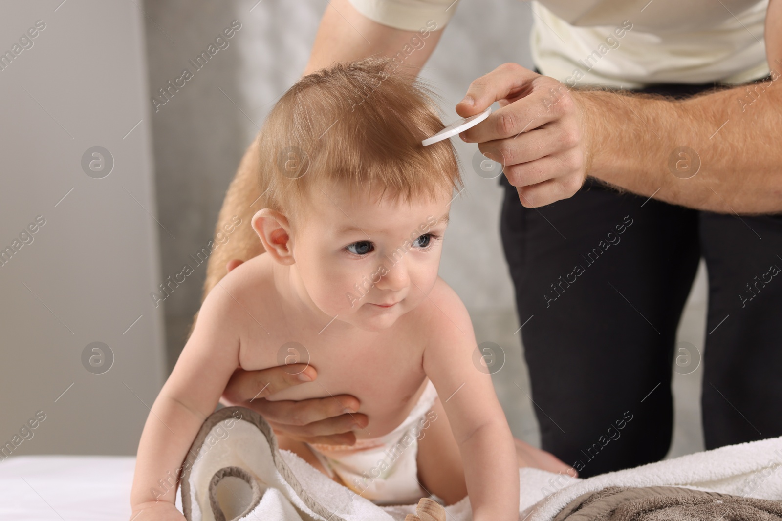 Photo of Man combing hair of his little baby indoors, closeup