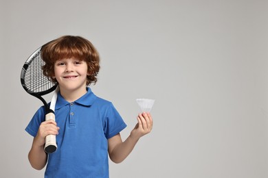 Photo of Little boy with badminton racket and shuttlecock on light grey background, space for text