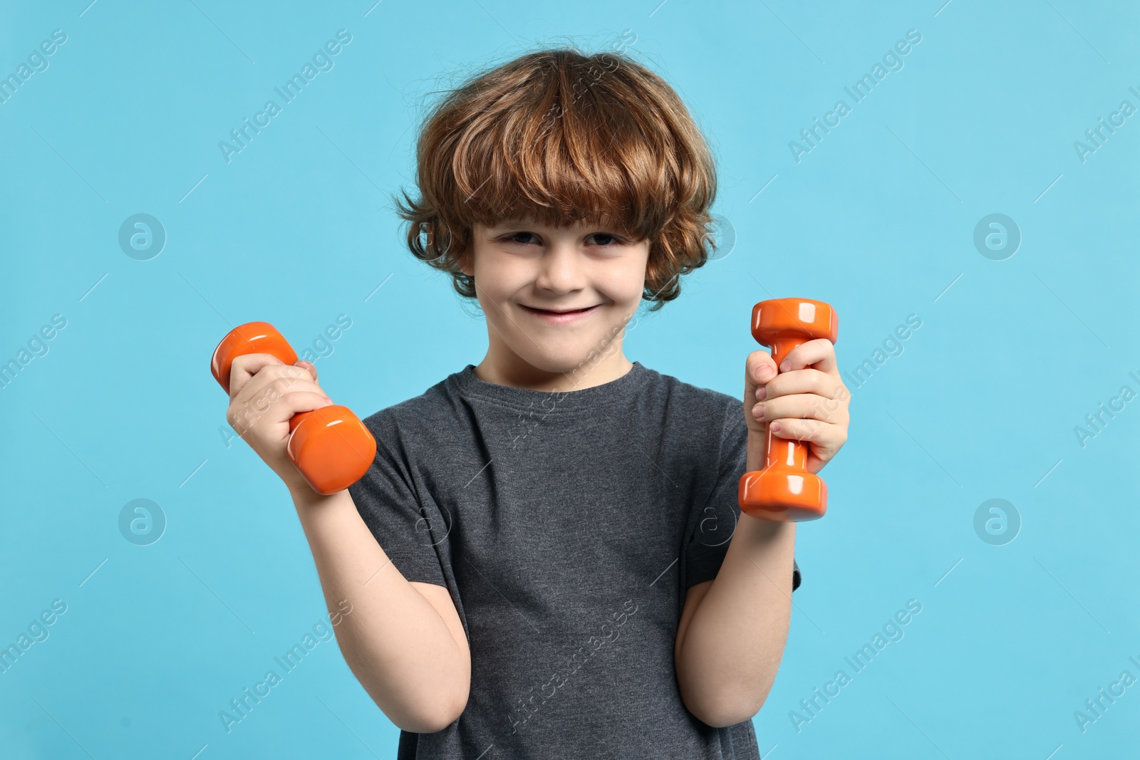 Photo of Little boy with dumbbells on light blue background