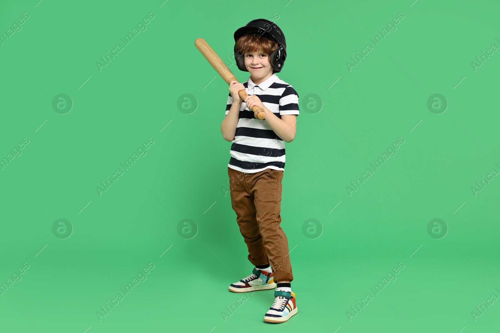 Photo of Little boy in helmet with baseball bat on light green background