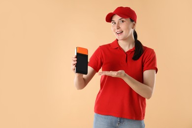 Happy courier with payment terminal on beige background, space for text