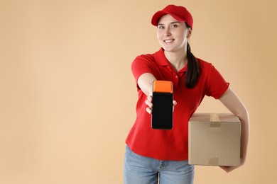 Happy courier with payment terminal and parcel on beige background, space for text