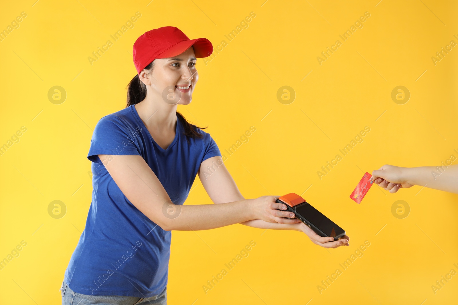 Photo of Courier taking payment from client via terminal on yellow background