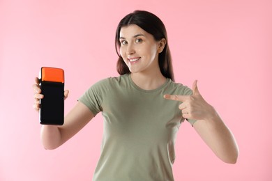 Photo of Happy young woman with payment terminal on pink background