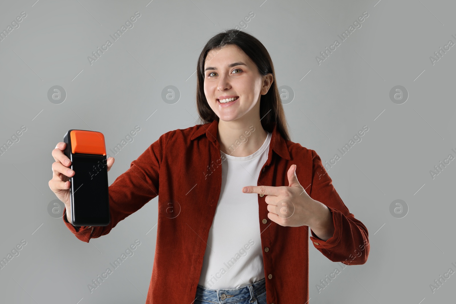 Photo of Happy young woman with payment terminal on gray background