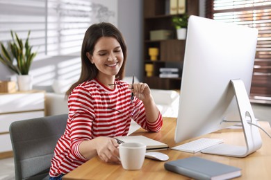 Photo of Happy woman working with computer at desk indoors. Home office