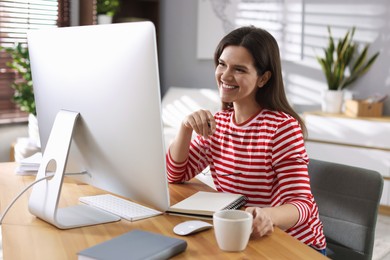 Photo of Happy woman working with computer at desk indoors. Home office