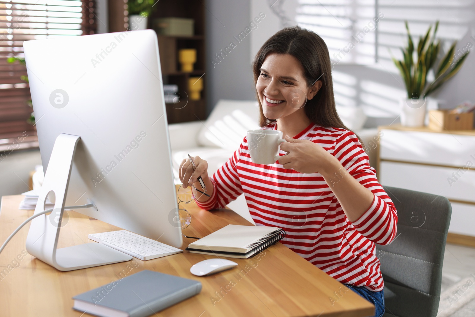 Photo of Happy woman working with computer at desk indoors. Home office