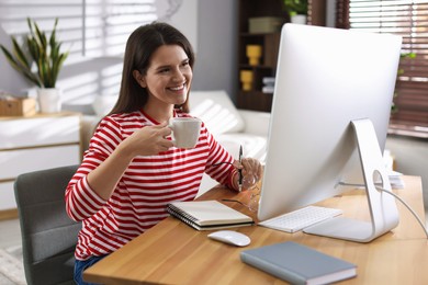 Photo of Happy woman working with computer at desk indoors. Home office