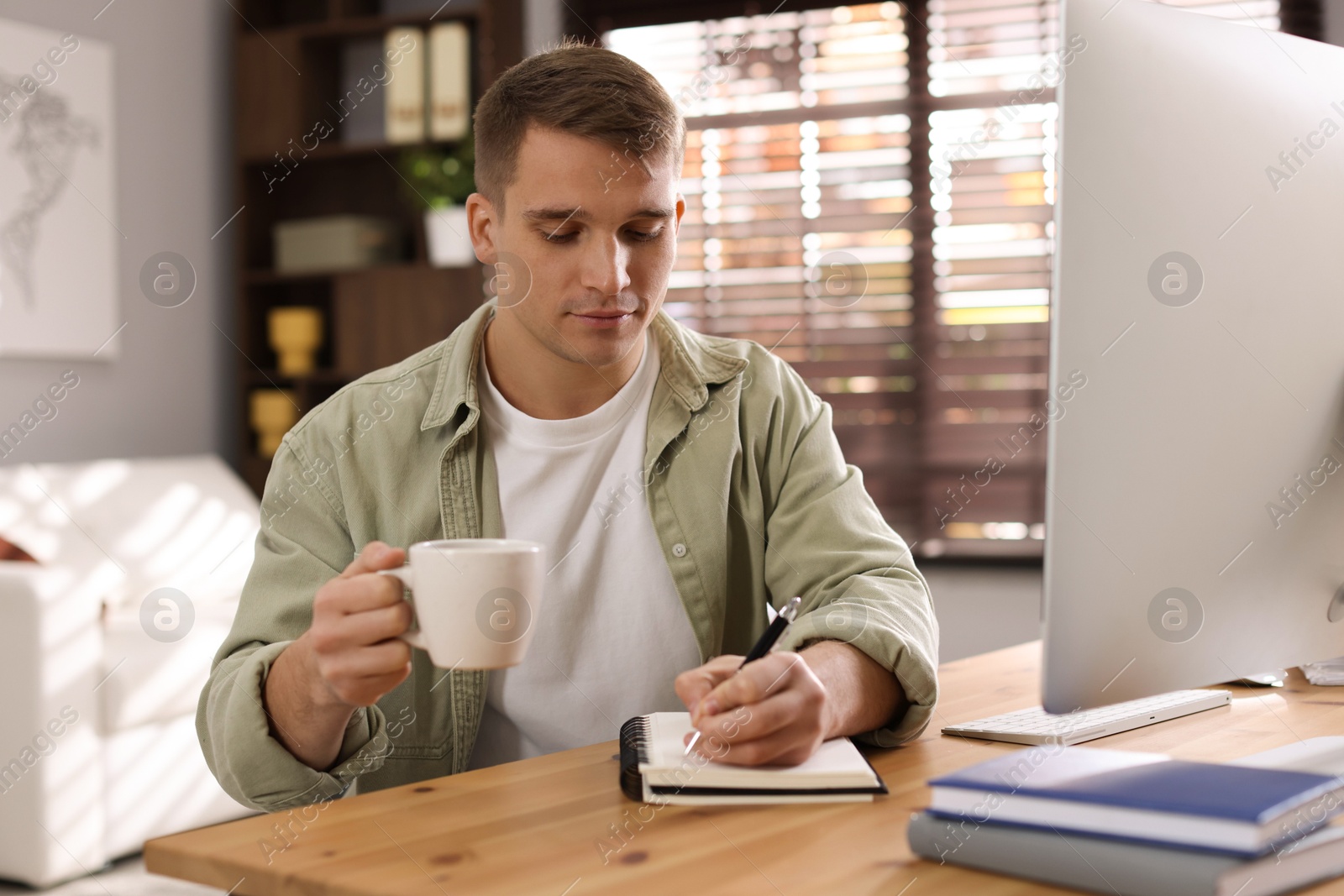 Photo of Handsome man working with computer at desk indoors. Home office