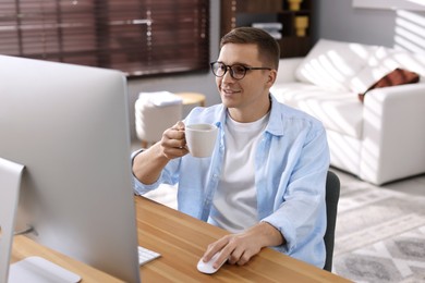 Photo of Happy man working with computer at desk indoors. Home office