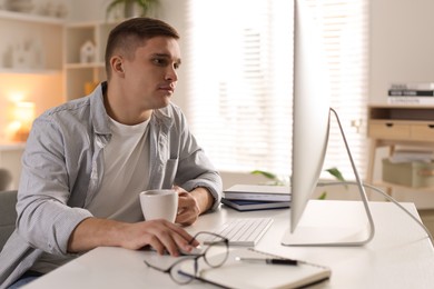 Photo of Handsome man working with computer at desk indoors. Home office