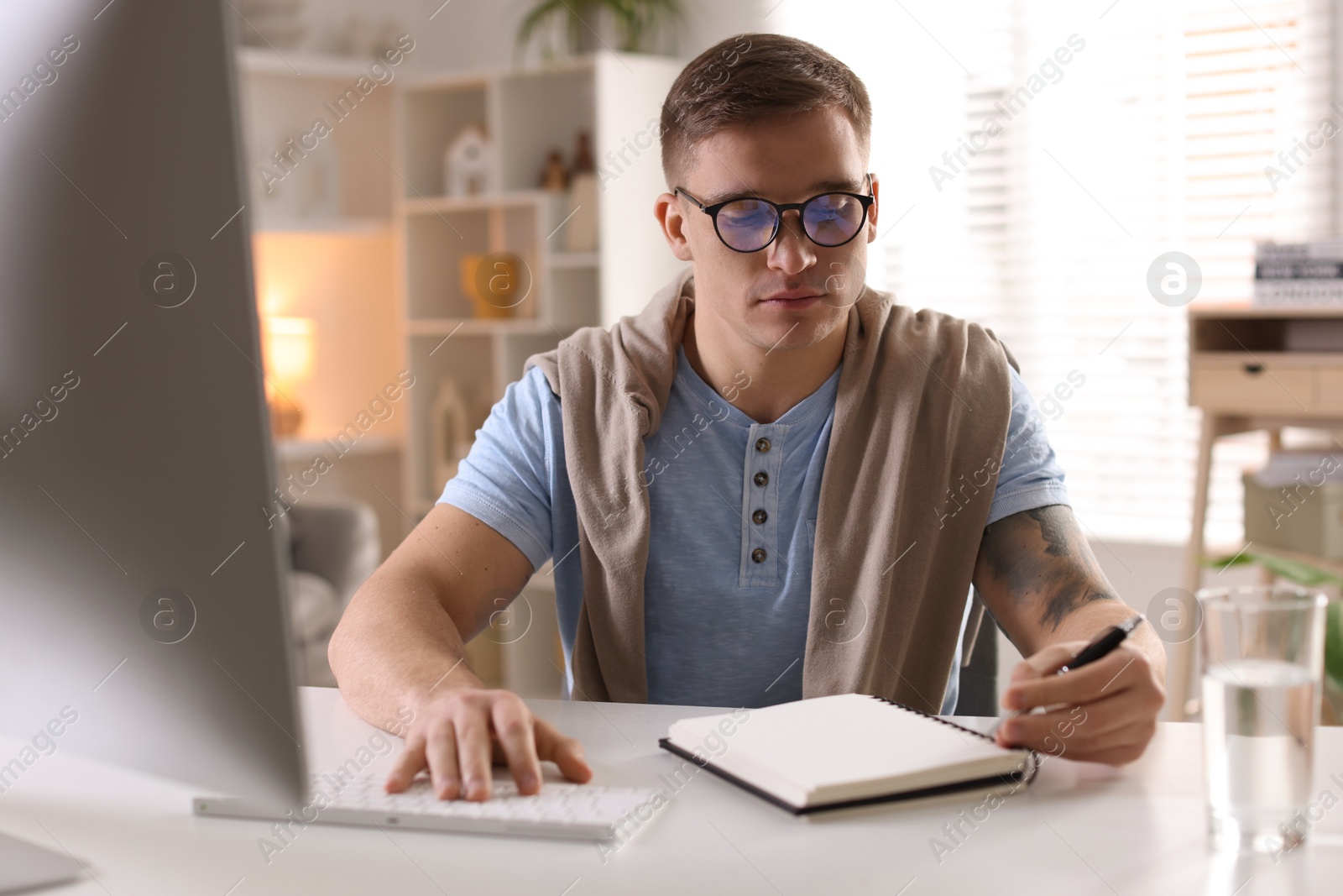 Photo of Handsome man working with computer at desk indoors. Home office