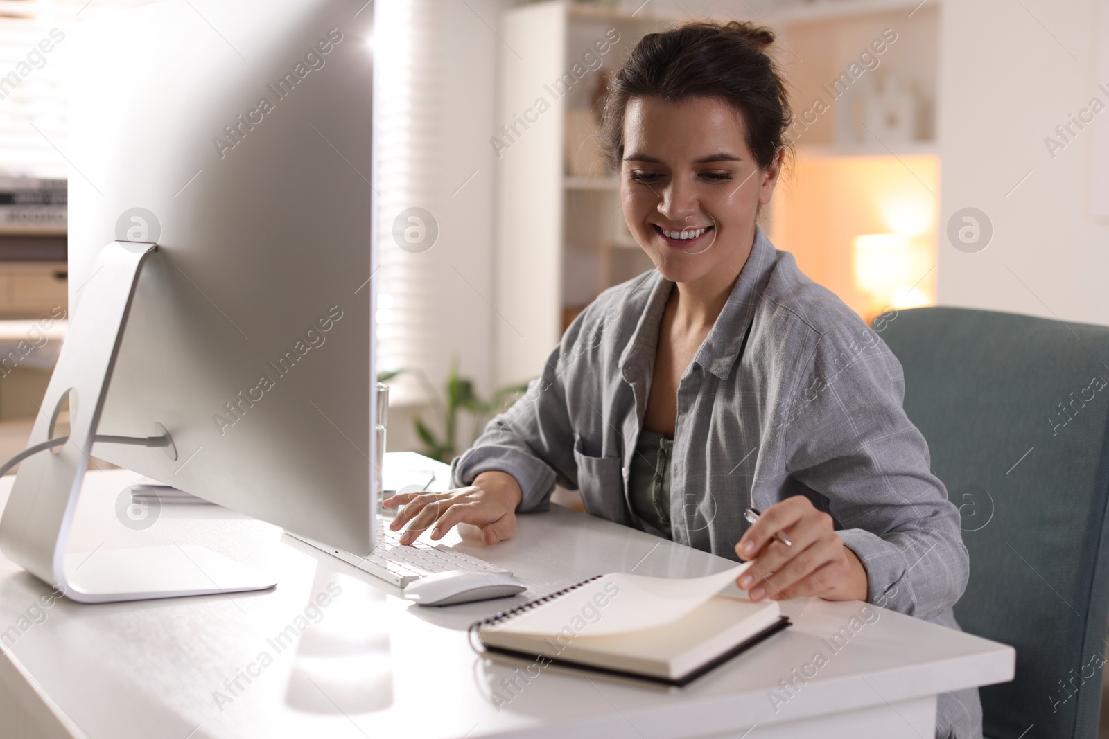 Photo of Happy woman working with computer at desk indoors. Home office