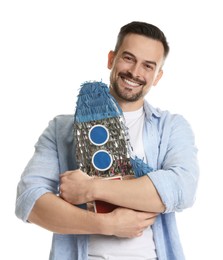 Happy man with rocket shaped pinata on white background