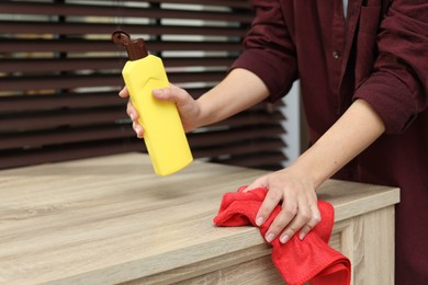 Photo of Woman polishing wooden table at home, closeup