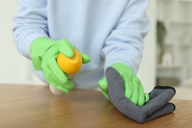 Photo of Woman polishing wooden table at home, closeup