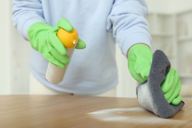 Photo of Woman polishing wooden table at home, closeup