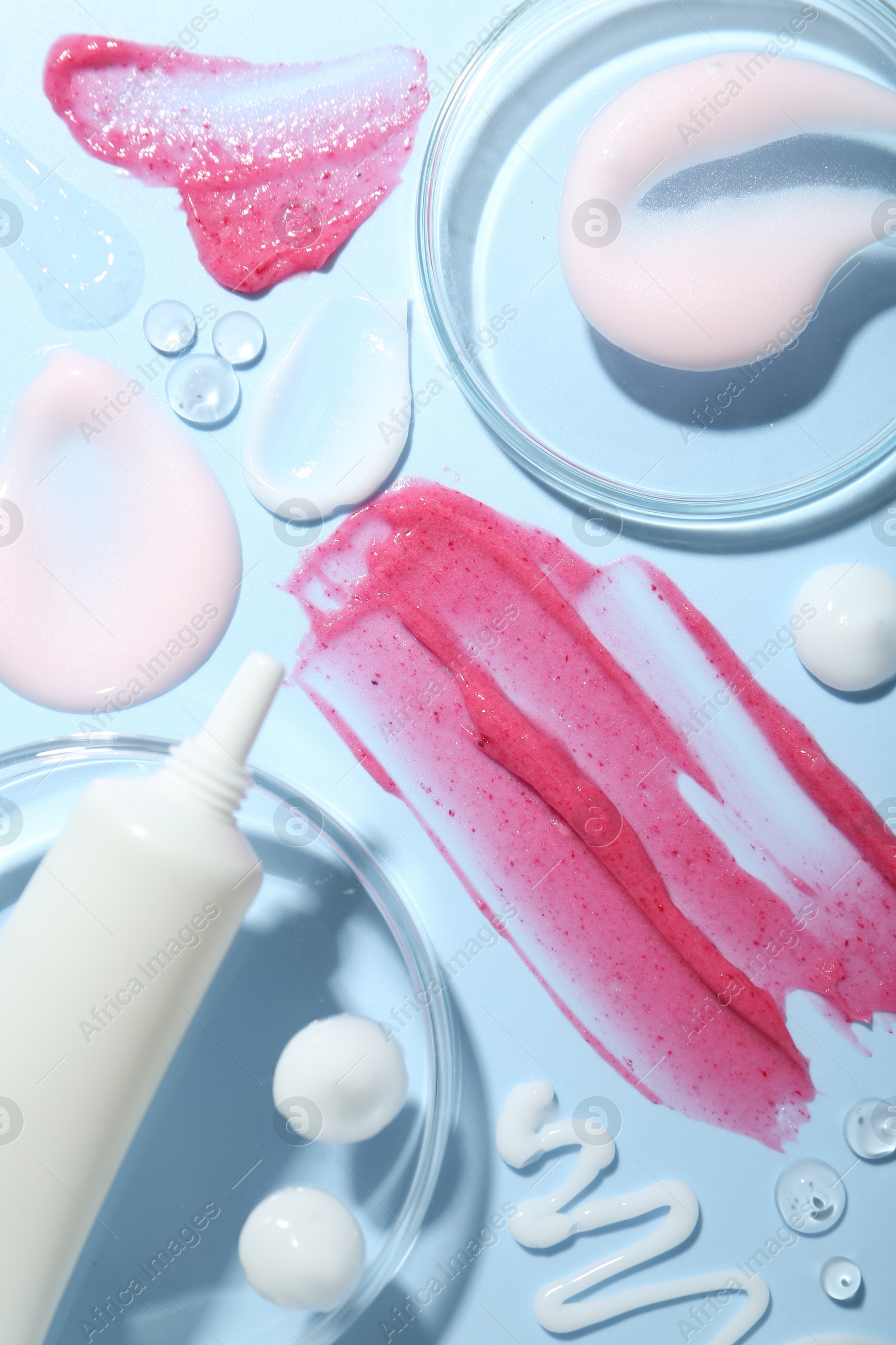 Photo of Cream, scrub and gel samples on light blue background, flat lay. Stylish presentation with tube of skincare product