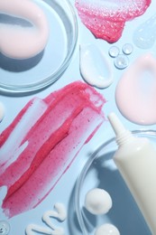 Photo of Cream, scrub and gel samples on light blue background, flat lay. Stylish presentation with tube of skincare product