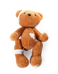 Photo of Teddy bear with bandages and adhesive medical plasters isolated on white, top view