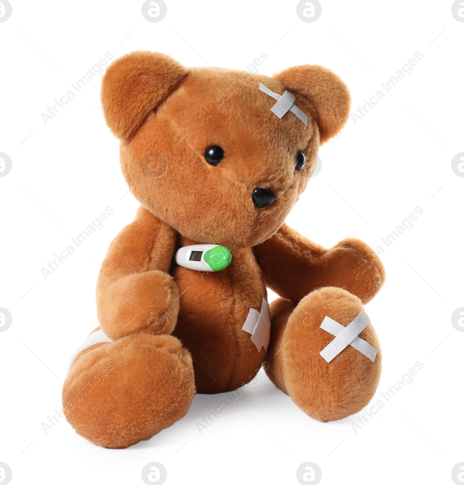 Photo of Teddy bear with bandage, adhesive medical plasters and thermometer isolated on white