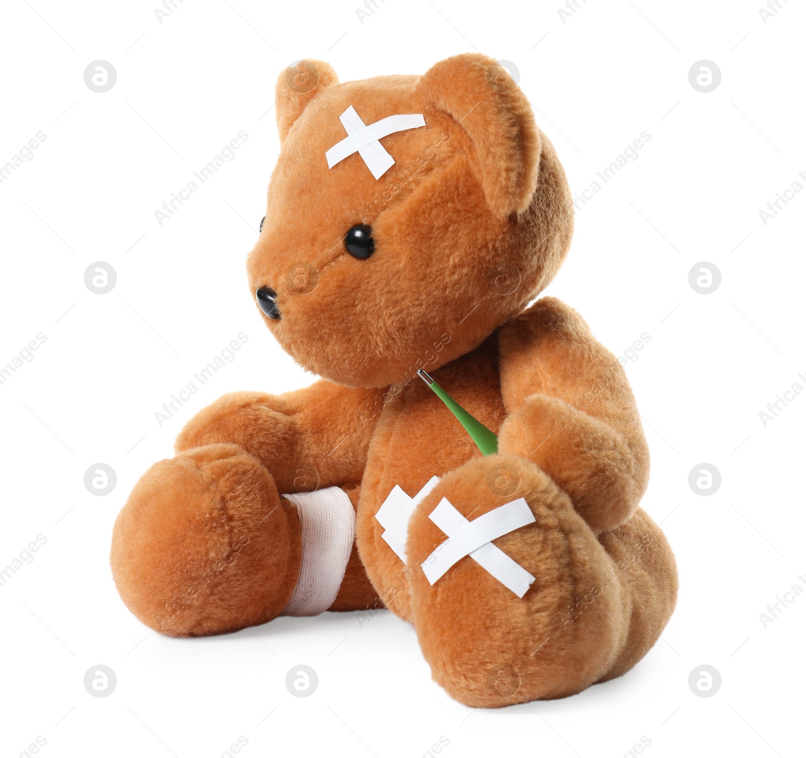 Photo of Teddy bear with bandage, adhesive medical plasters and thermometer isolated on white