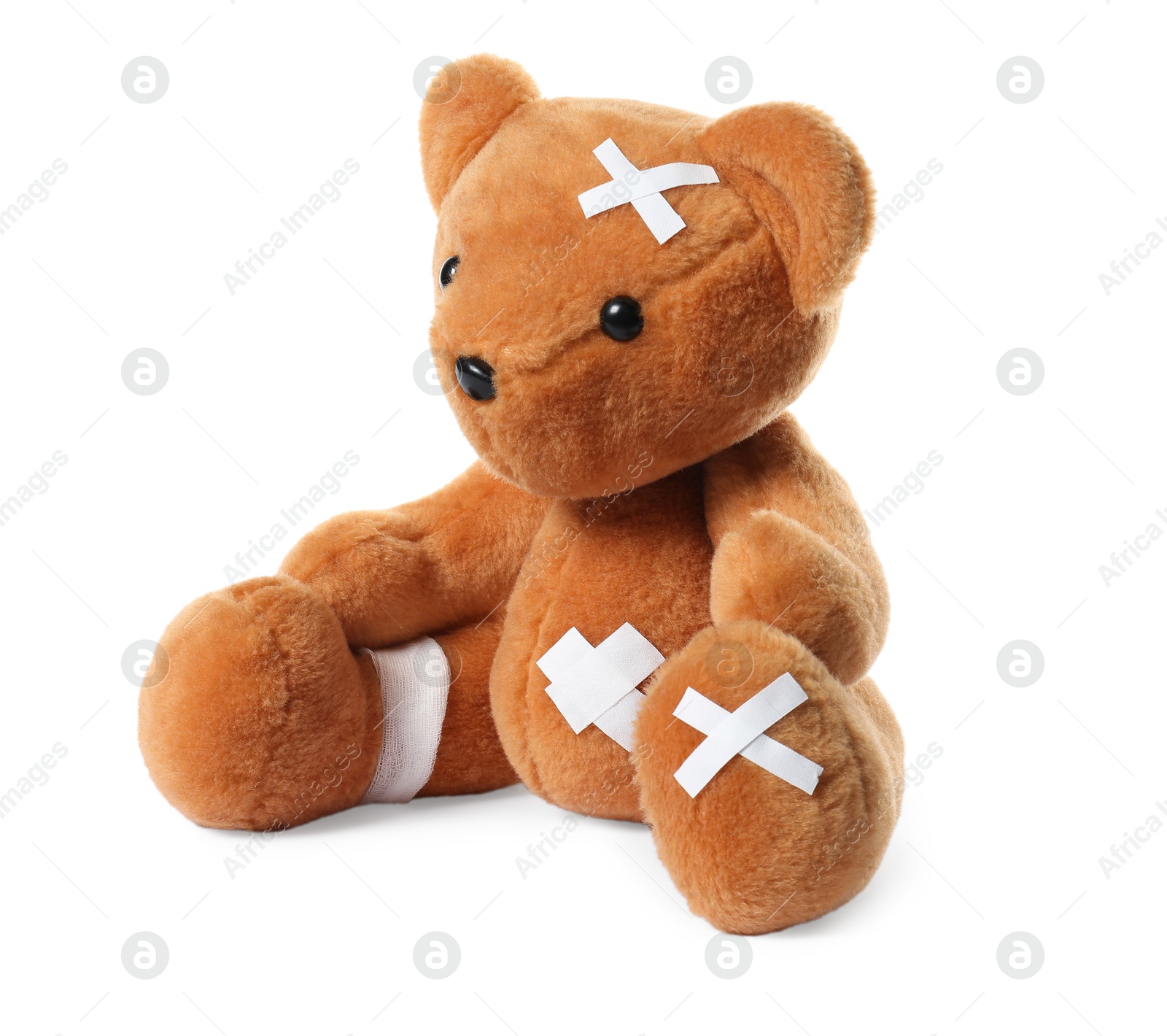 Photo of Teddy bear with bandage and adhesive medical plasters isolated on white