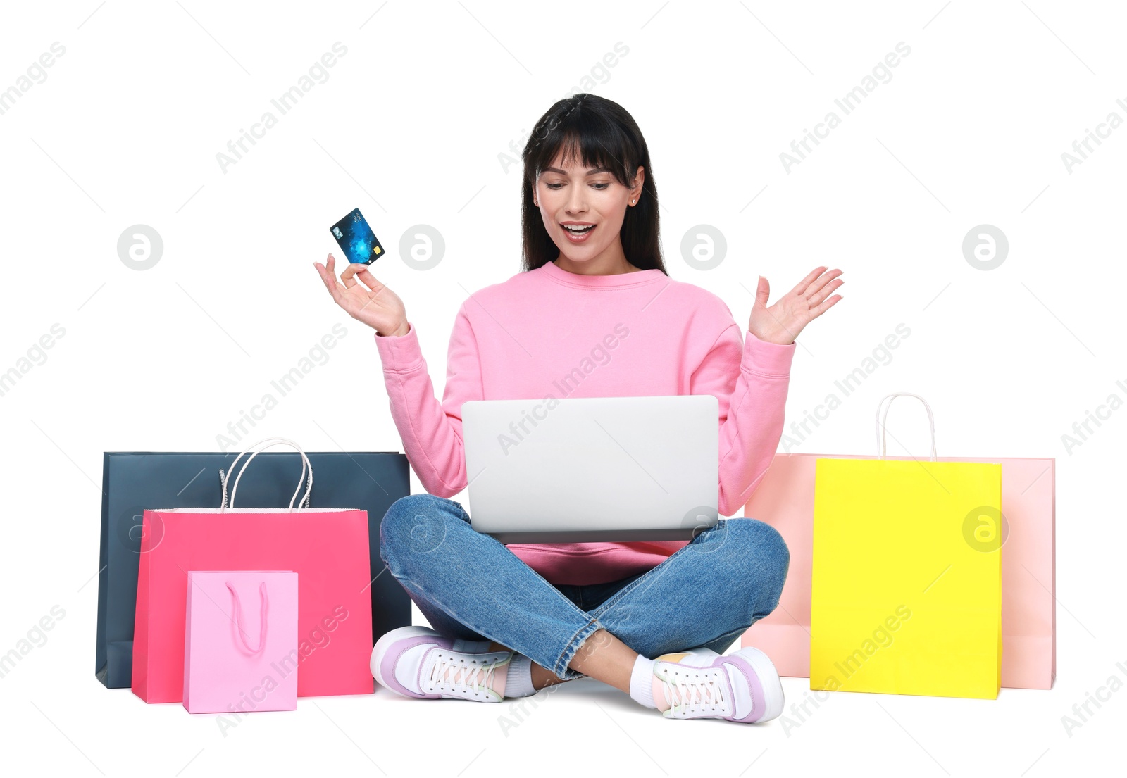 Photo of Internet shopping. Surprised woman with credit card, laptop and colorful bags on white background