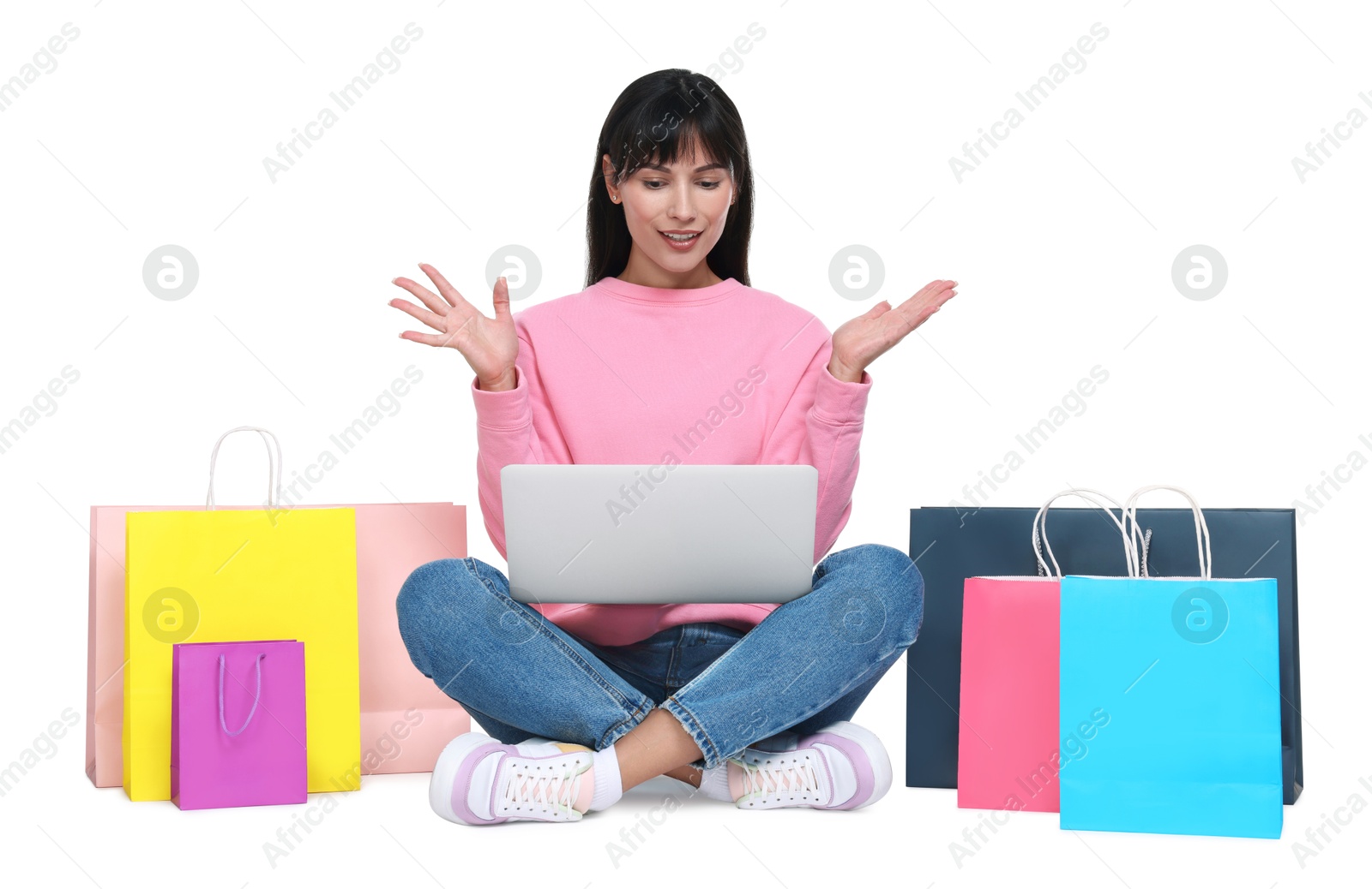 Photo of Internet shopping. Surprised woman with laptop and colorful bags on white background