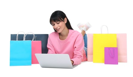 Photo of Internet shopping. Smiling woman with laptop and colorful bags on white background