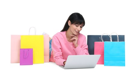 Photo of Internet shopping. Smiling woman with laptop and colorful bags on white background