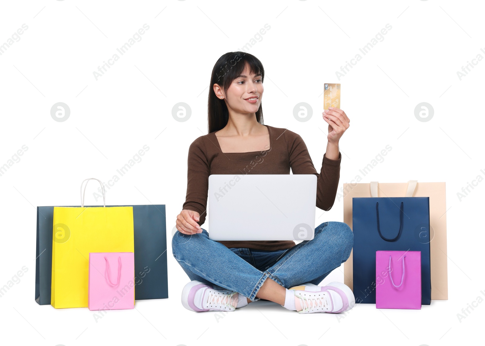 Photo of Internet shopping. Happy woman with credit card, laptop and colorful bags on white background