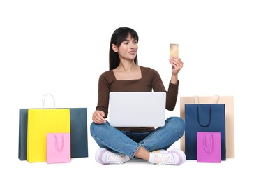 Internet shopping. Happy woman with credit card, laptop and colorful bags on white background