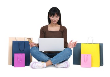 Internet shopping. Beautiful woman with credit card, laptop and colorful bags on white background