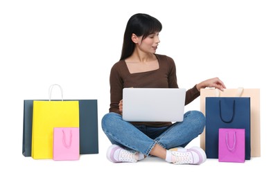 Photo of Internet shopping. Beautiful woman with laptop and colorful bags on white background