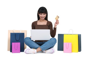 Internet shopping. Happy woman with credit card, laptop and colorful bags on white background