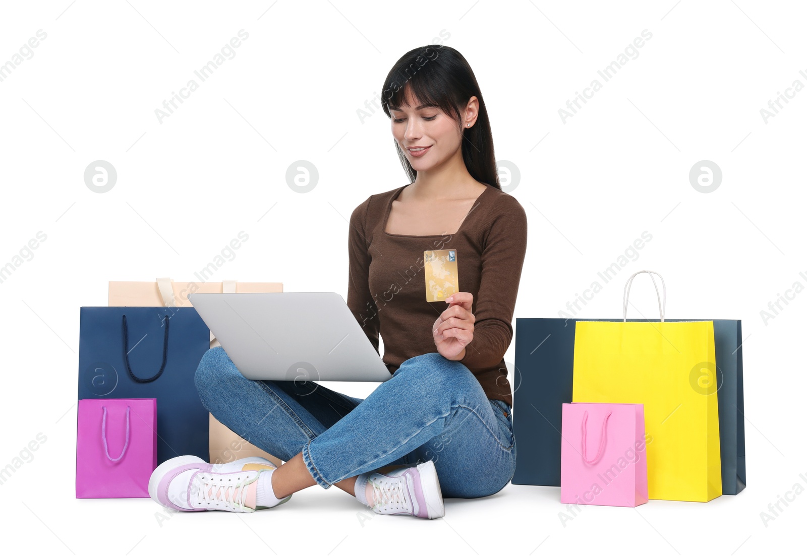 Photo of Internet shopping. Happy woman with credit card, laptop and colorful bags on white background