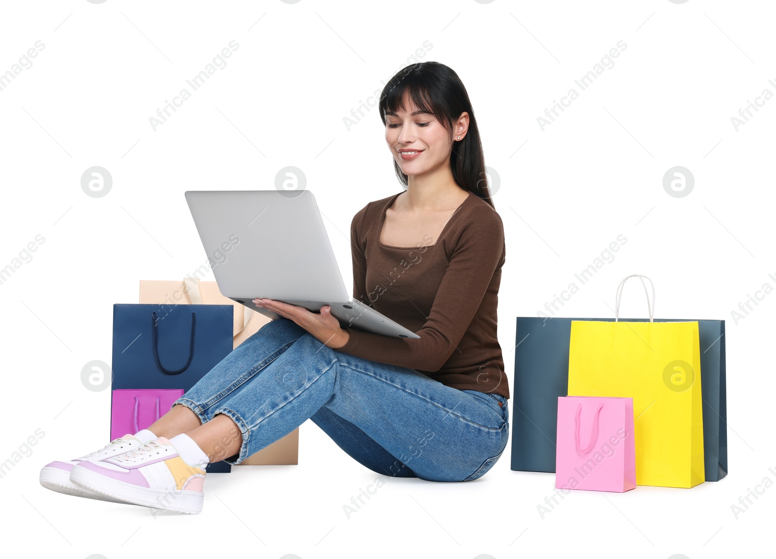 Photo of Internet shopping. Happy woman with laptop and colorful bags on white background