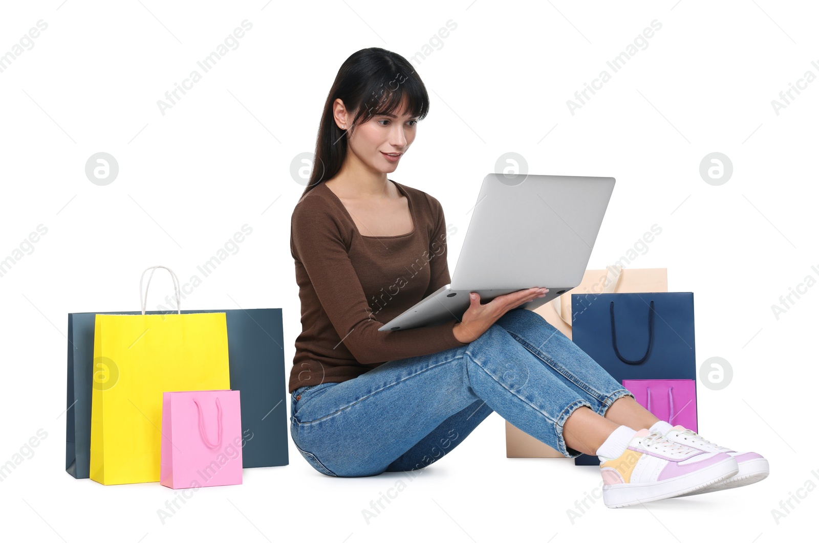 Photo of Internet shopping. Beautiful woman with laptop and colorful bags on white background