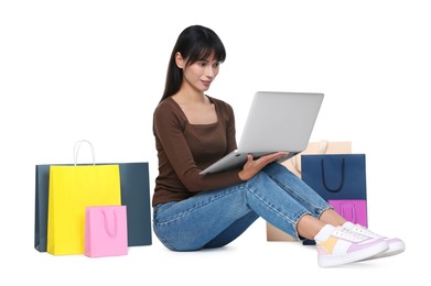 Internet shopping. Beautiful woman with laptop and colorful bags on white background