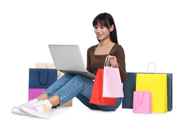 Photo of Internet shopping. Happy woman with laptop and colorful bags on white background