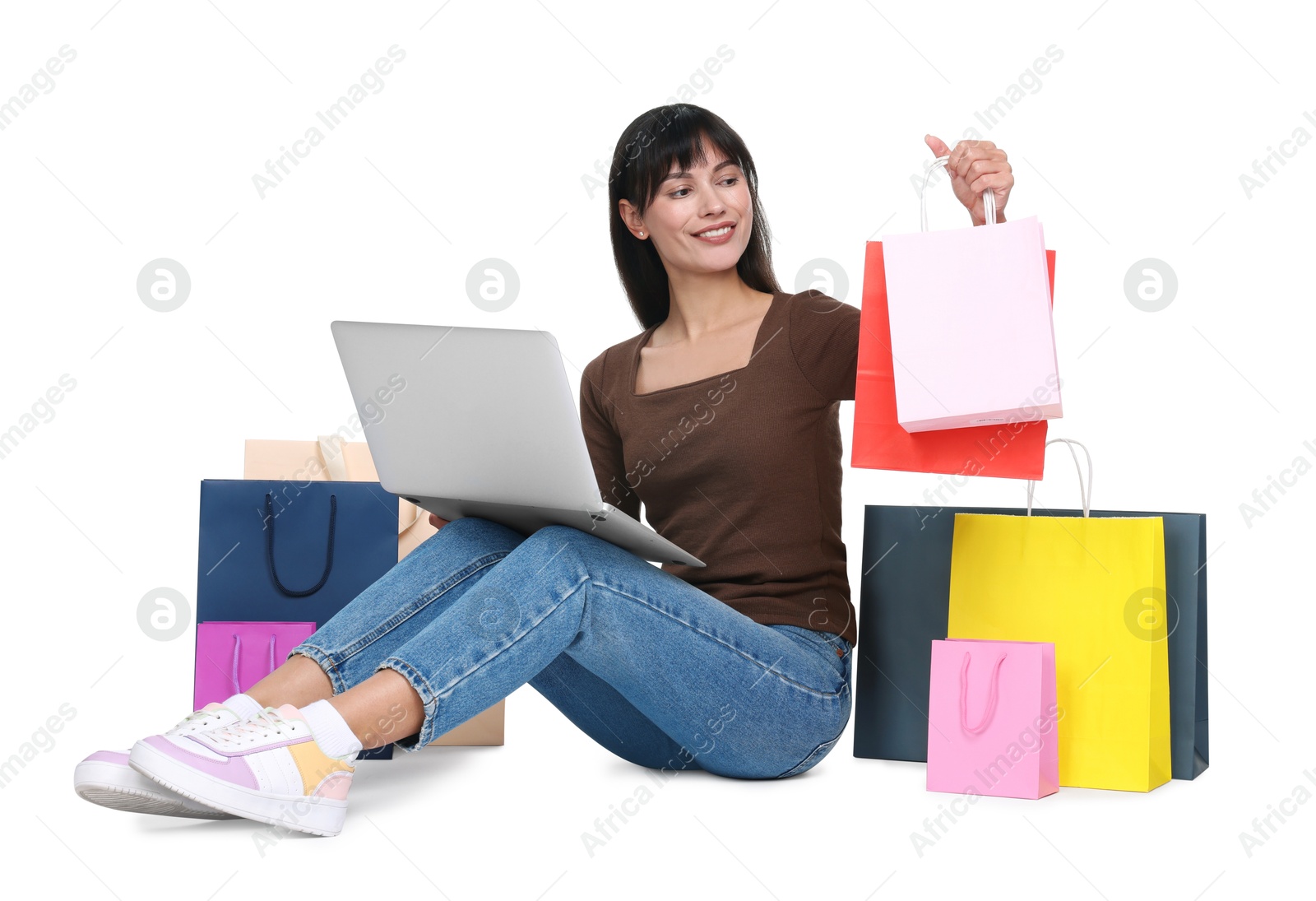 Photo of Internet shopping. Happy woman with laptop and colorful bags on white background