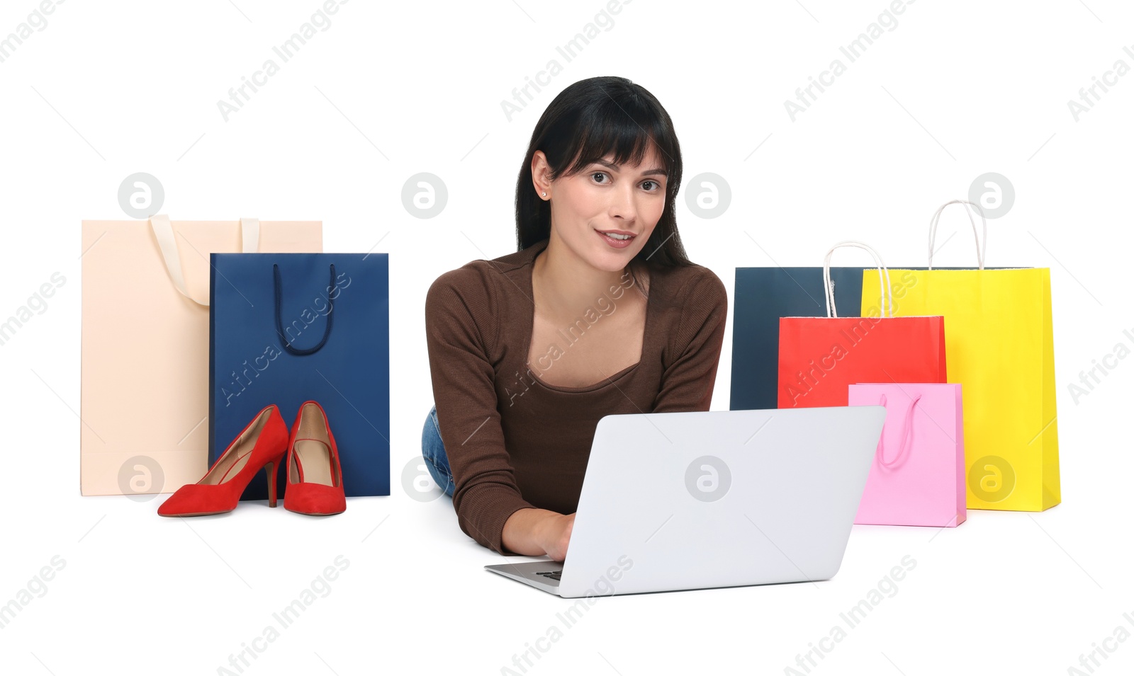 Photo of Internet shopping. Happy woman with laptop and colorful bags on white background