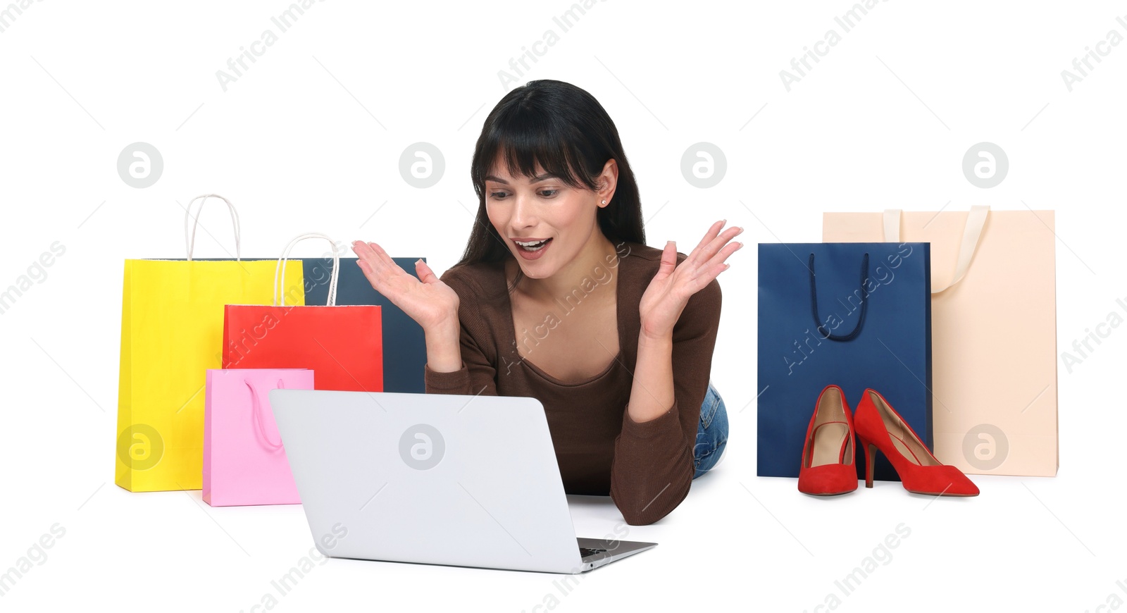 Photo of Internet shopping. Surprised woman with laptop and colorful bags on white background