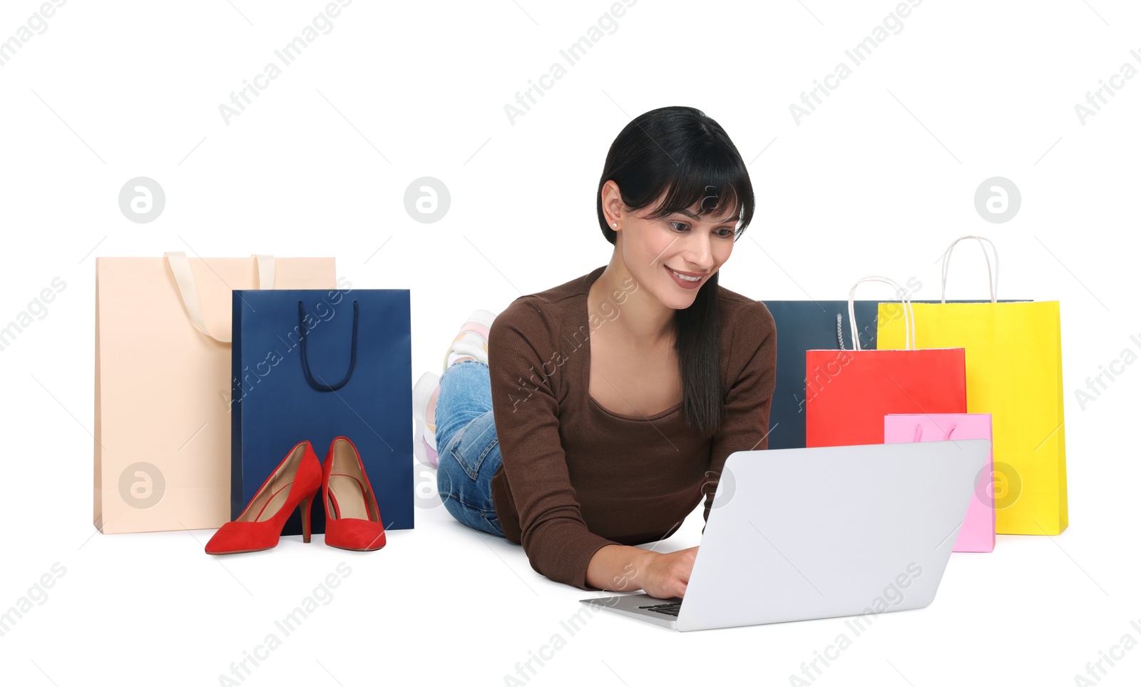 Photo of Internet shopping. Happy woman with laptop and colorful bags on white background