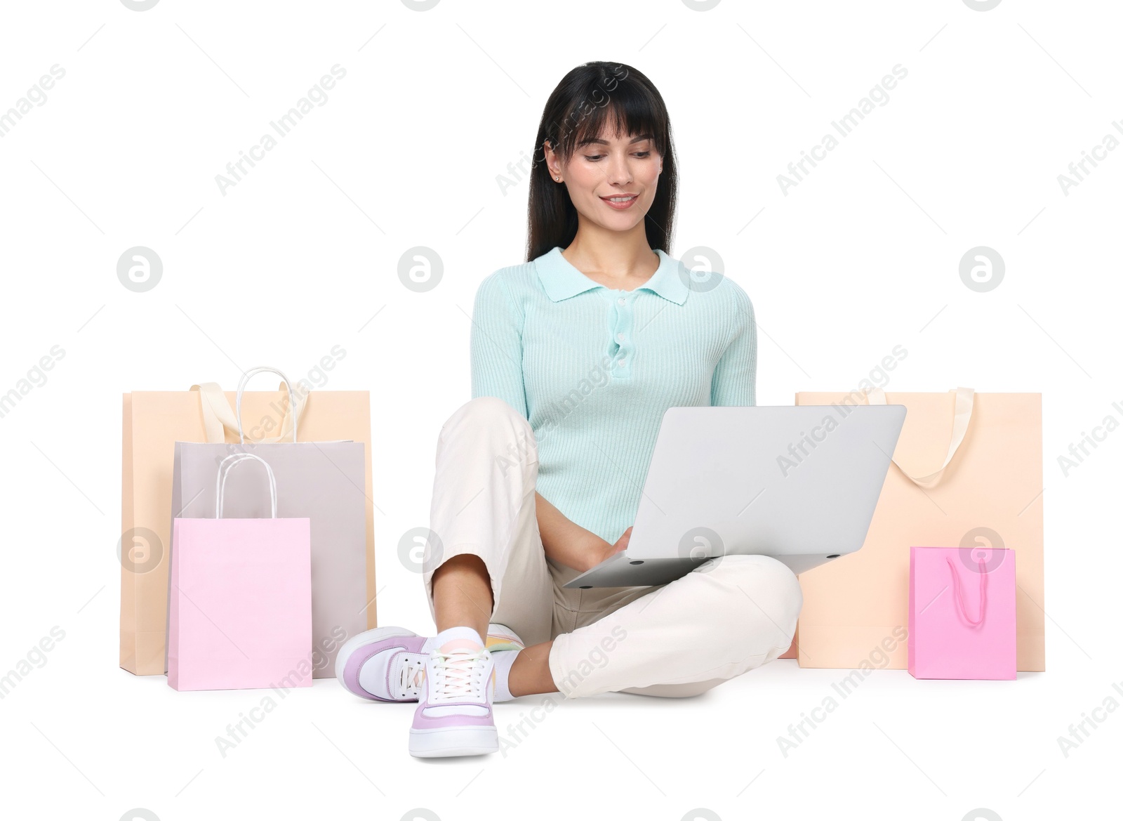 Photo of Internet shopping. Happy woman with laptop and colorful bags on white background