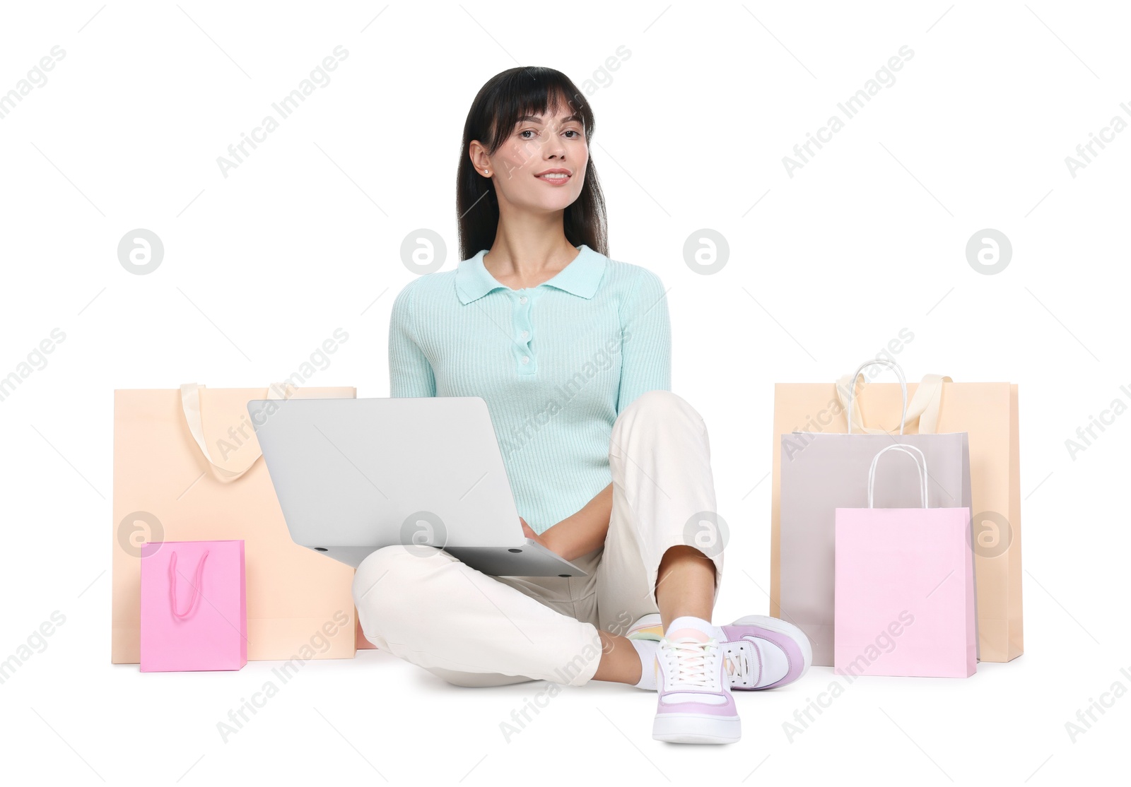 Photo of Internet shopping. Happy woman with laptop and colorful bags on white background