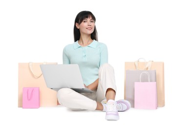 Internet shopping. Happy woman with laptop and colorful bags on white background