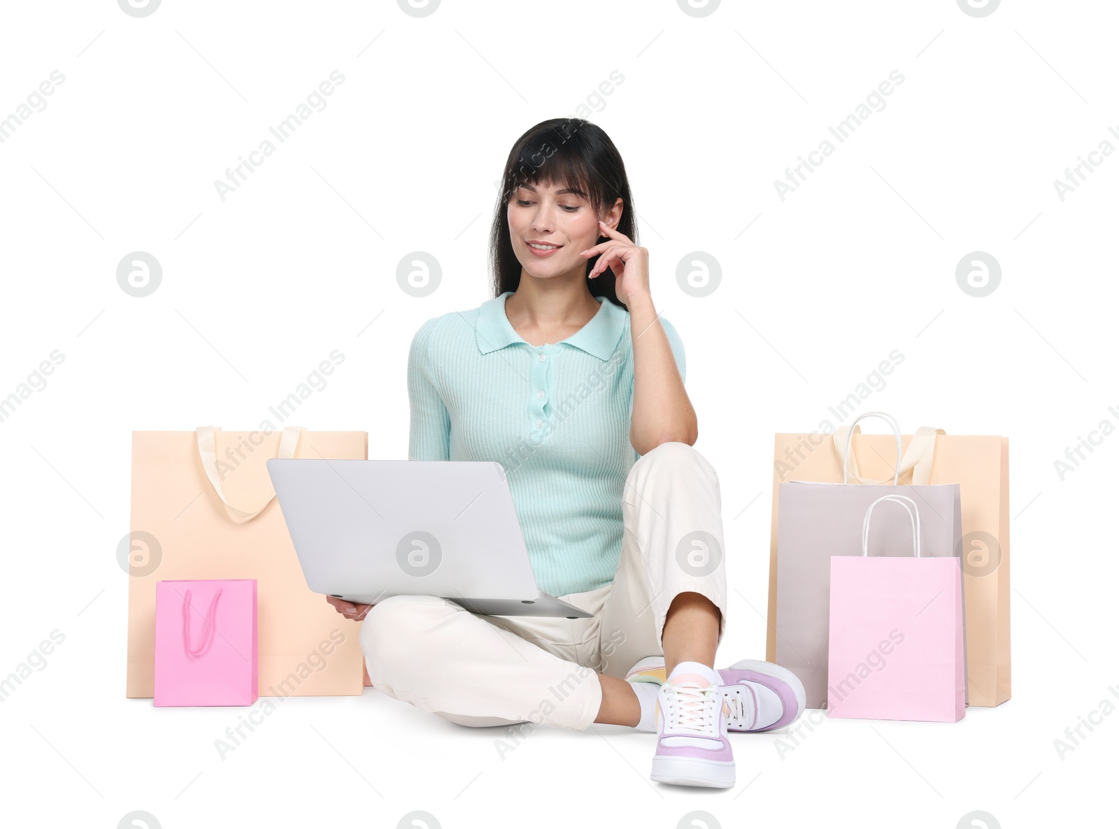 Photo of Internet shopping. Happy woman with laptop and colorful bags on white background